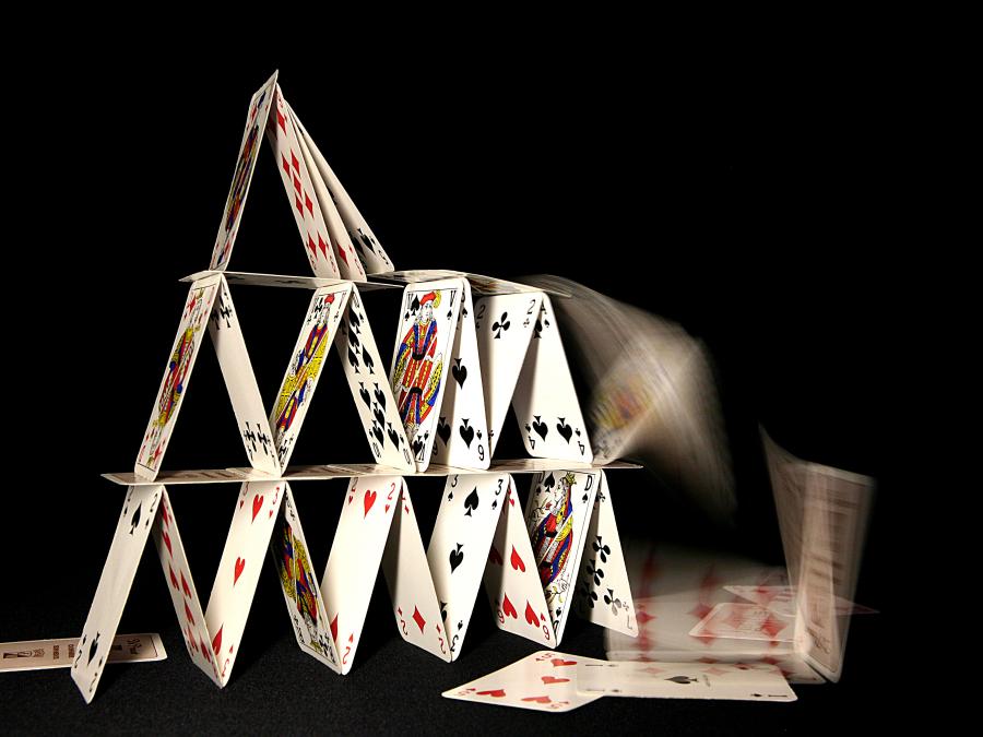House of cards collapsing on dark background